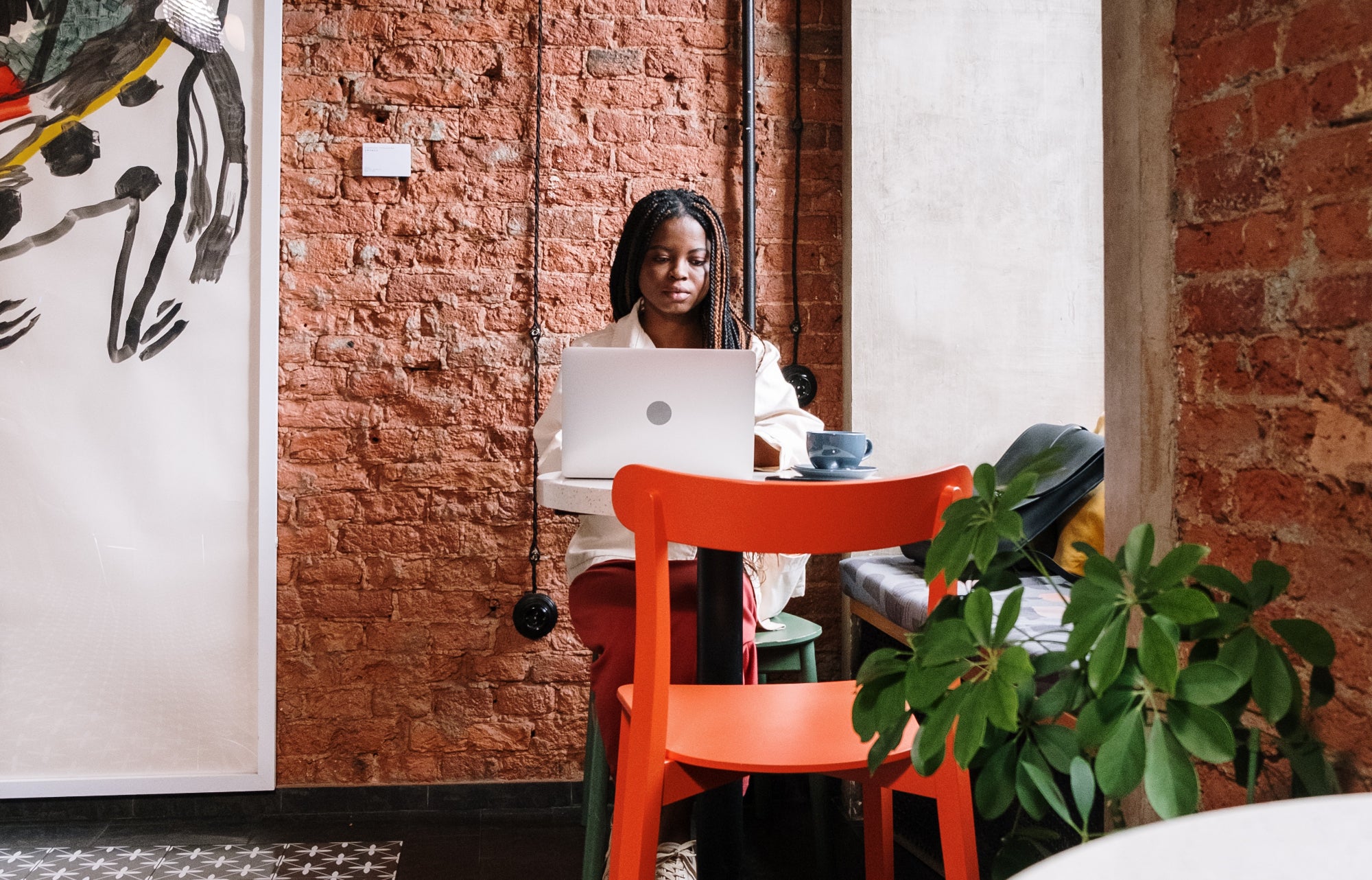 Person sits in a gallery cafe at a small table working on a laptop