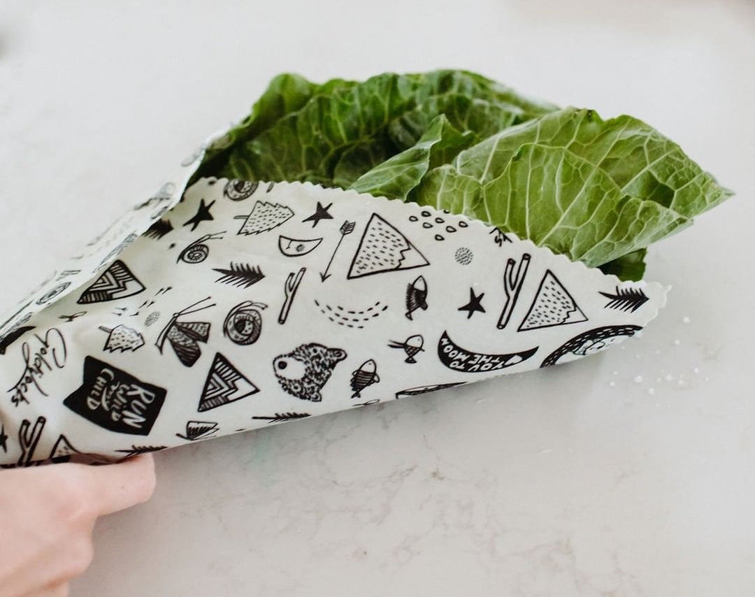 Hand holds lettuce wrapped with a piece of Goldilocks beeswax food wrap