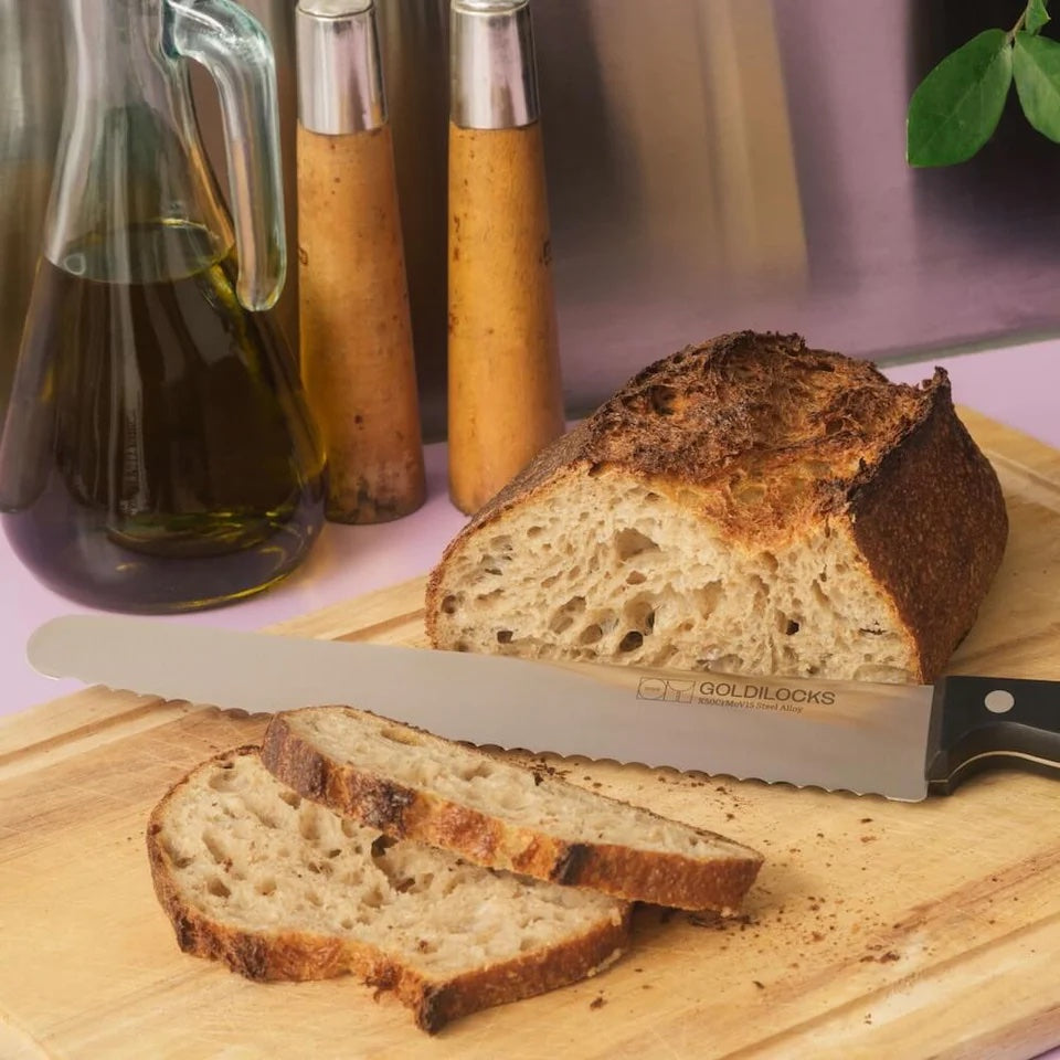 Stainless steel large breadknife next to a loaf of sliced bread.