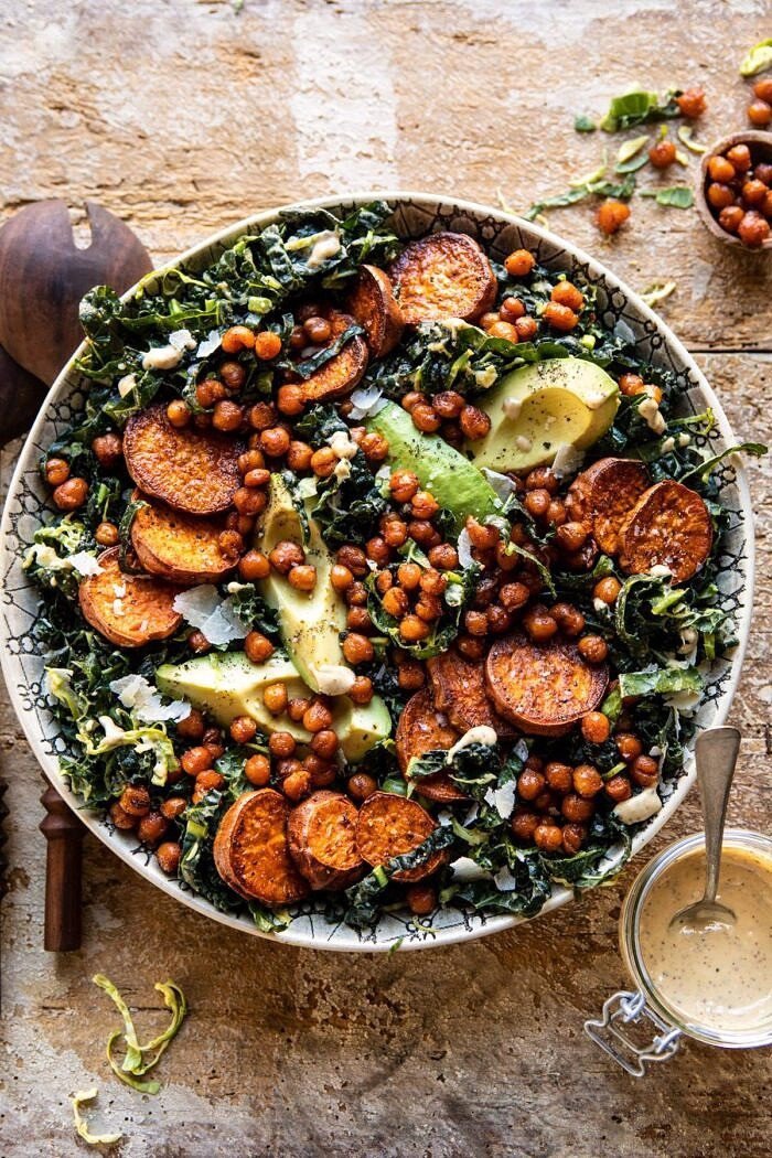 A bowl of kale caesar salad with yams, avocado, and chickpeas 