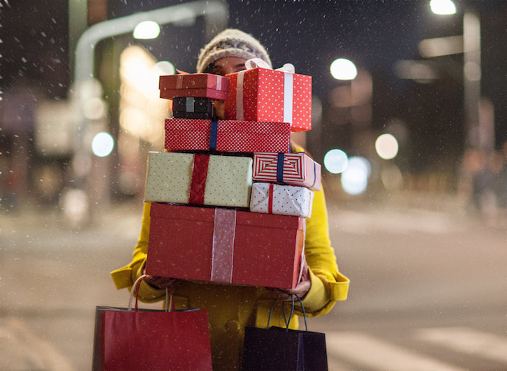 Jemand hält einen Stapel Geschenke in der Hand und braucht eine gute Kundenbetreuung zu Weihnachten.