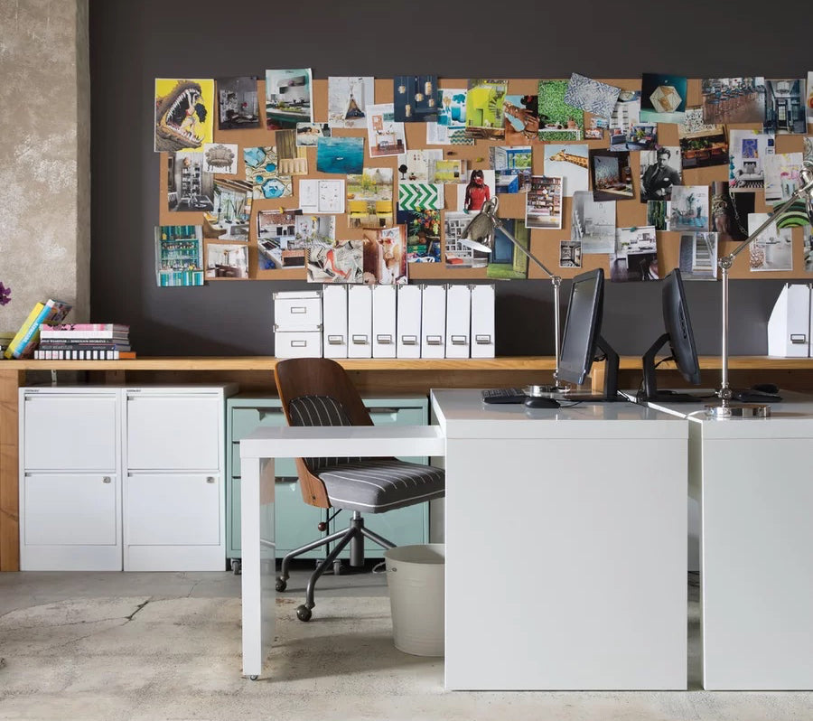 A home office featuring multiple white filing cabinets and an oversized bulletin board packed with inspirational images
