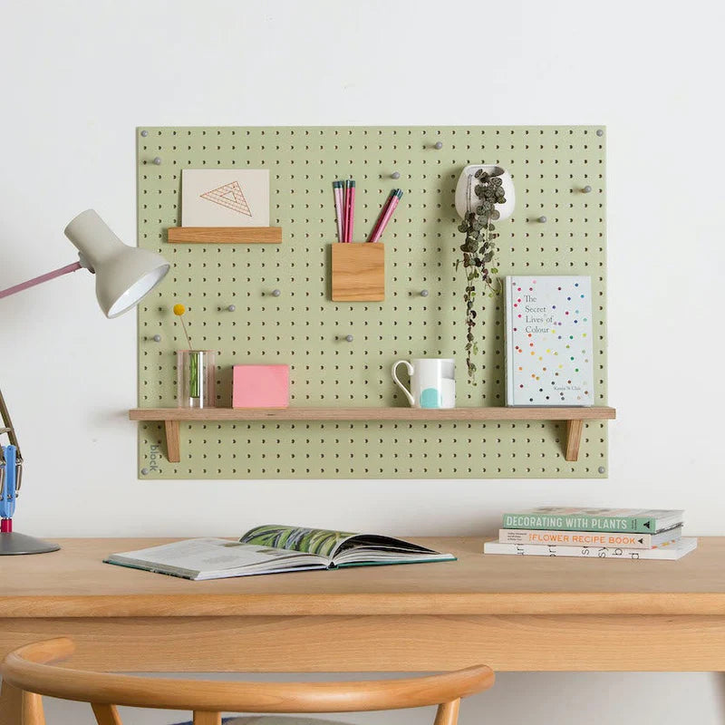 Tight shot of a workspace featuring a green pegboard holding multiple office supplies