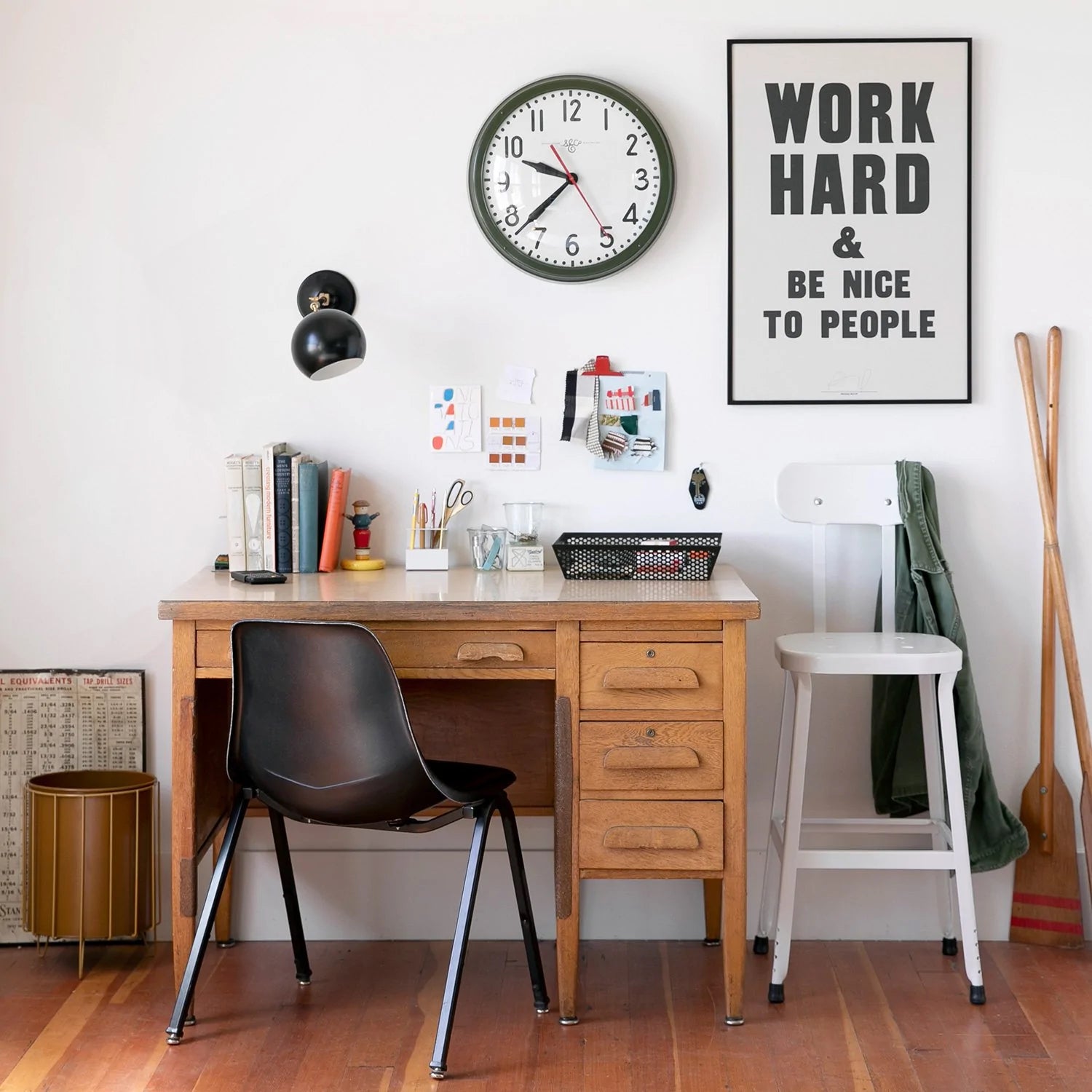 A home office featuring a large inspirational poster that reads "work hard and be nice to people"