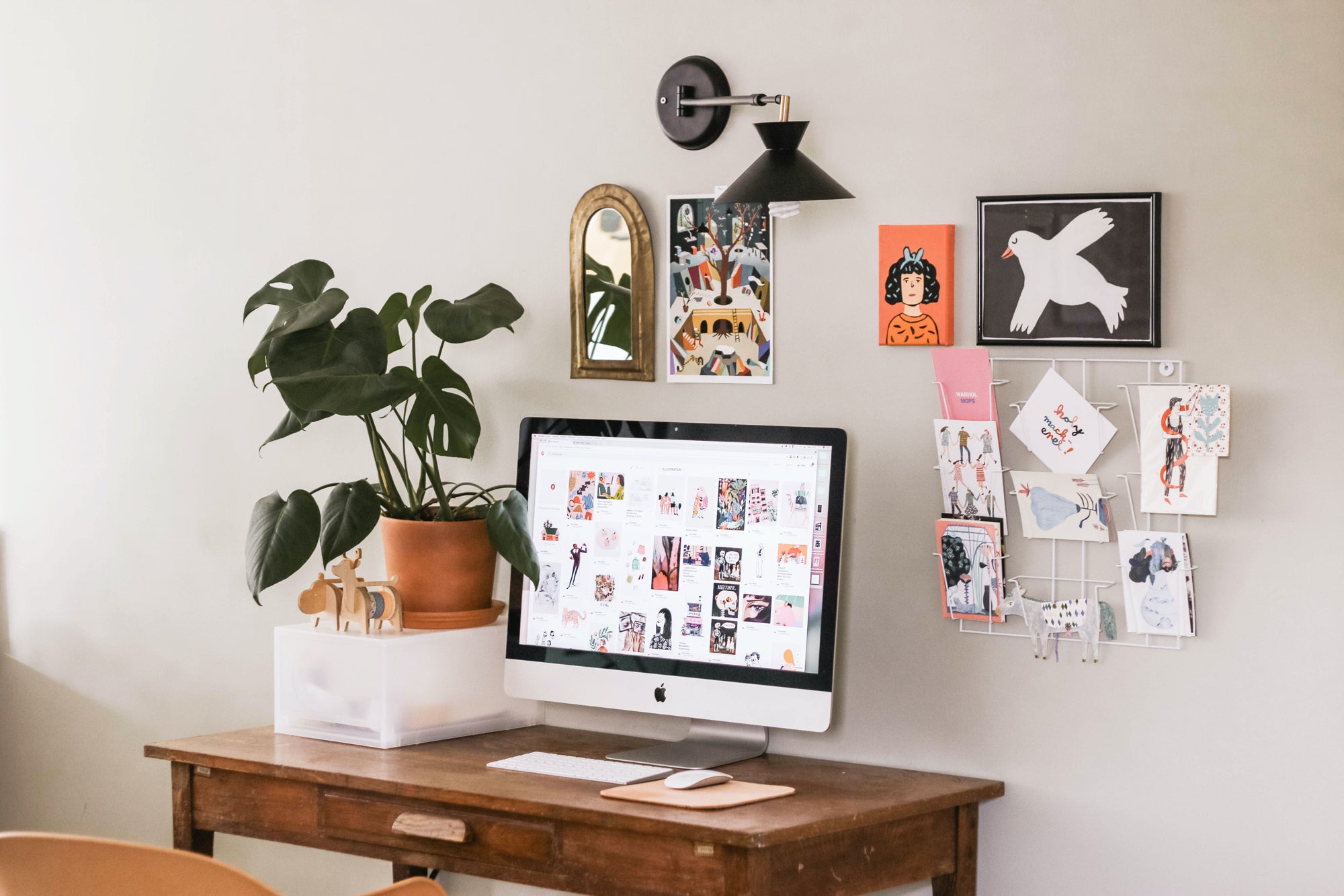 A small workspace with wall art, a large plant, and a computer