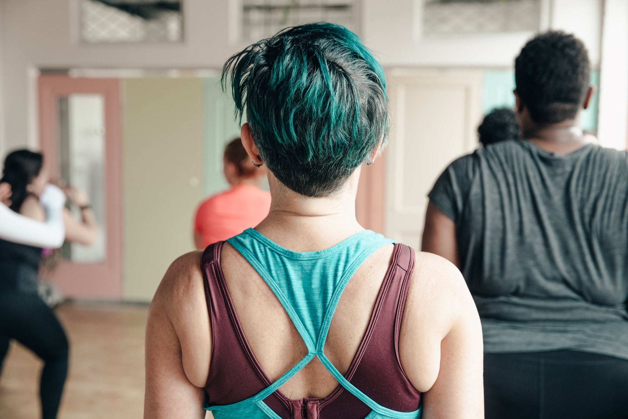 Shot from behind, a person attends a fitness class with other people