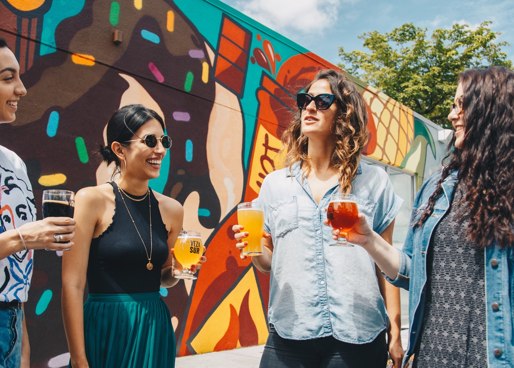 People hold drinks and talk in an outdoor urban setting