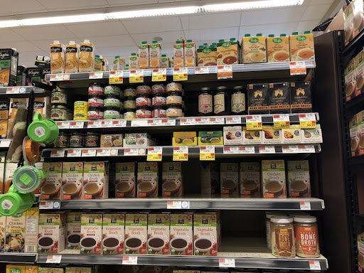 crowded grocery store shelves stocked with broth and stock