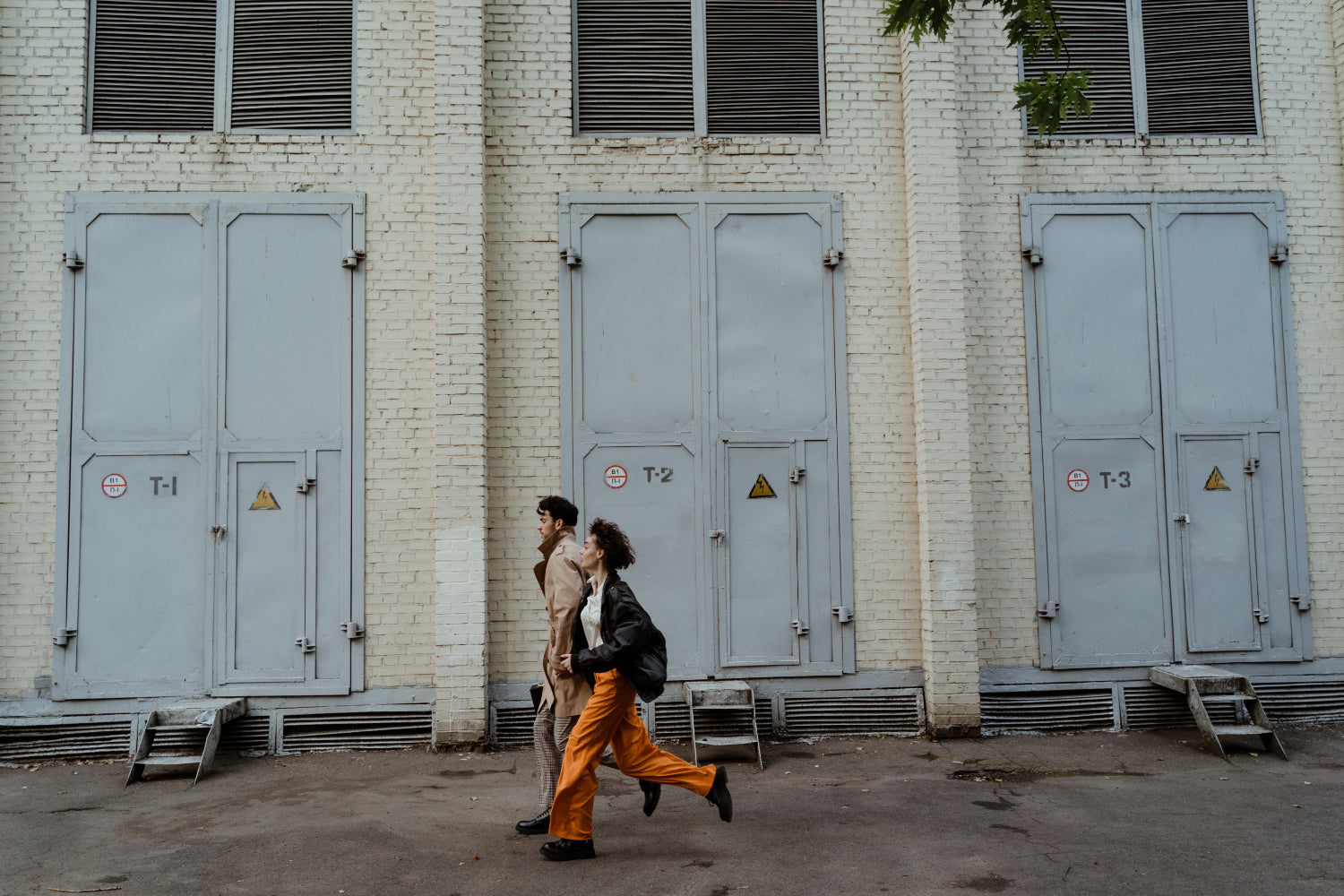 Two people jog past a large warehouse