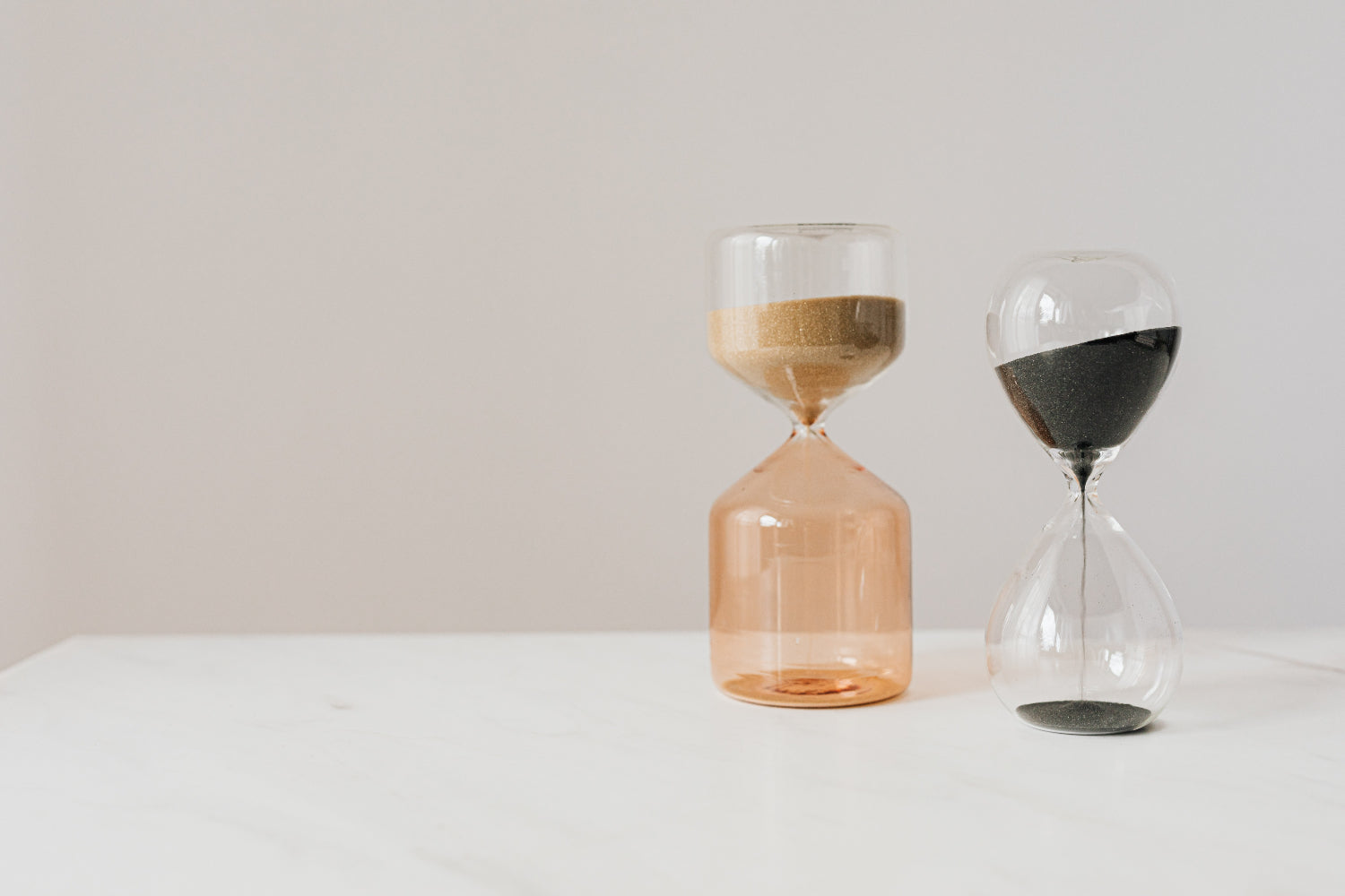 Two glass sand timers grouped against a neutral background