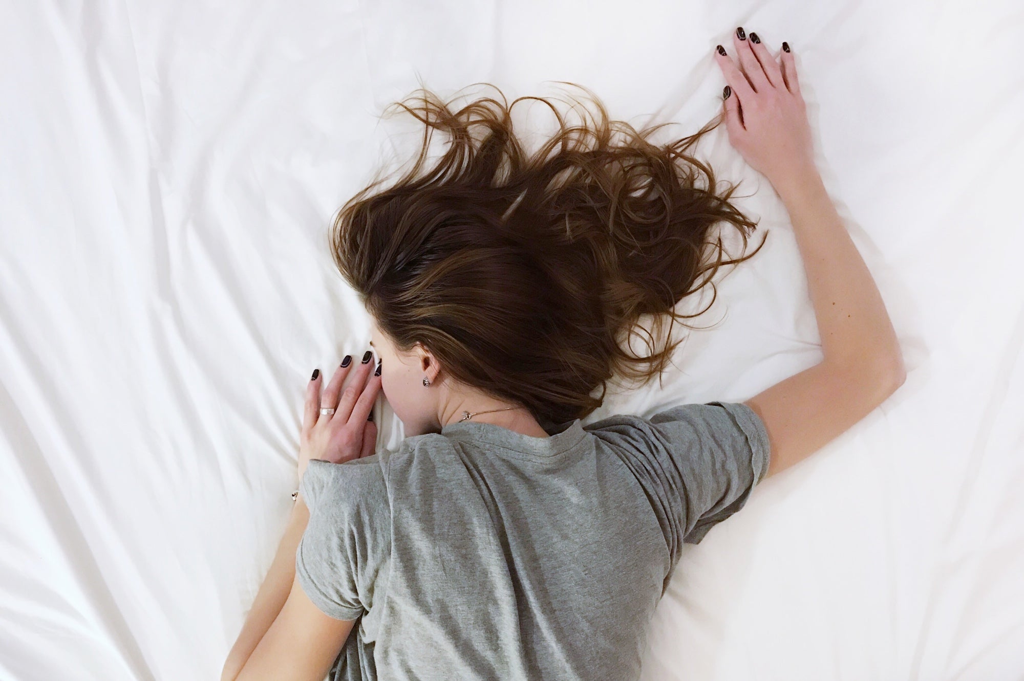 A person shot from above naps on a white bed