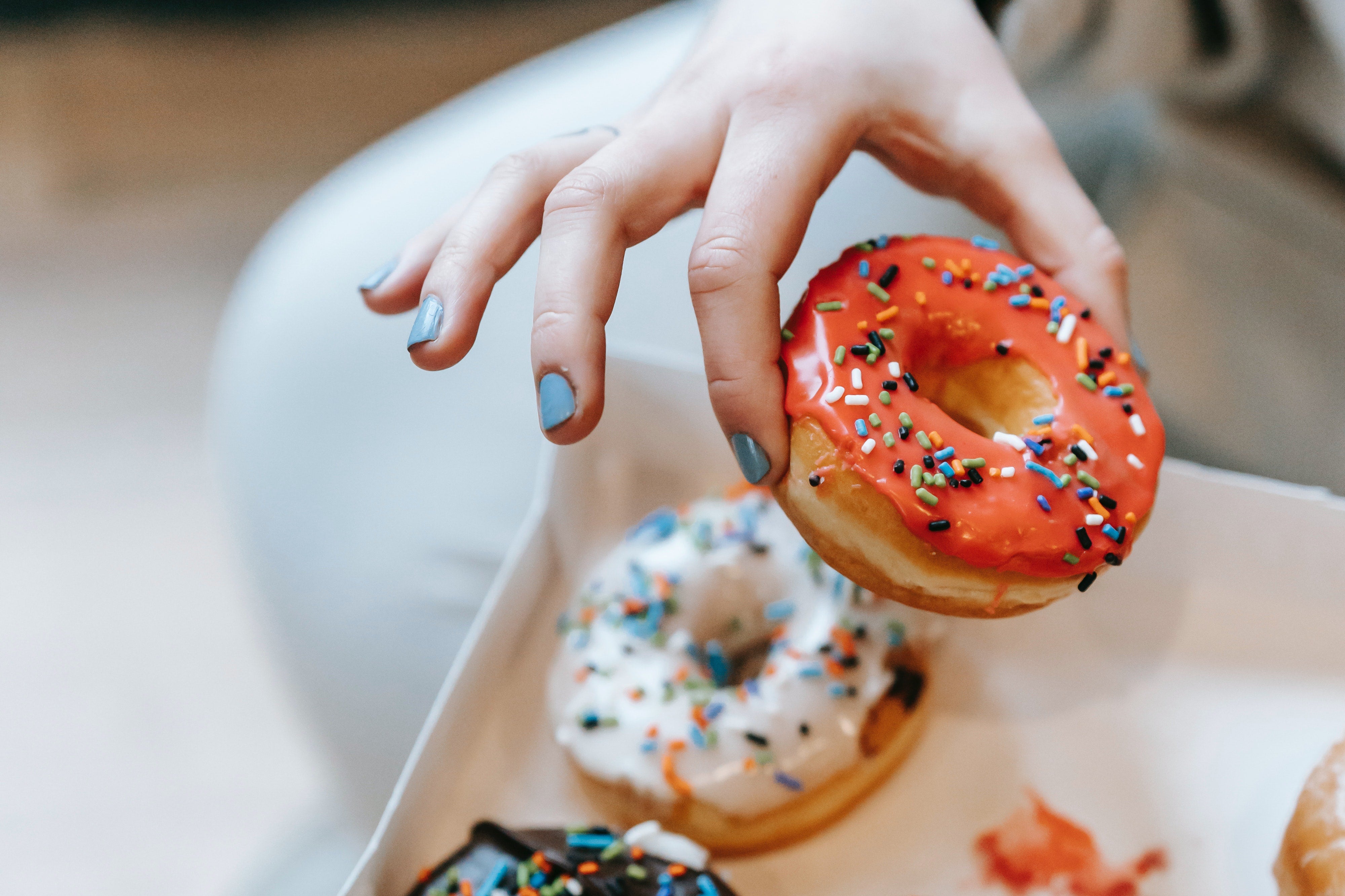 A hand grabs a donut from a box