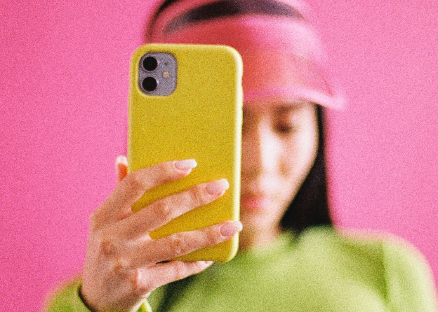 Woman holds up a yellow mobile phone in front of her face