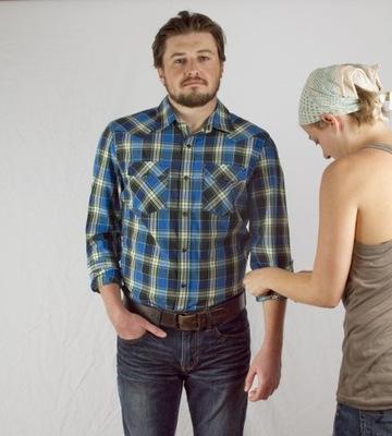 Eine Person bereitet ein Model auf ein Kleidungsfotoshooting vor.