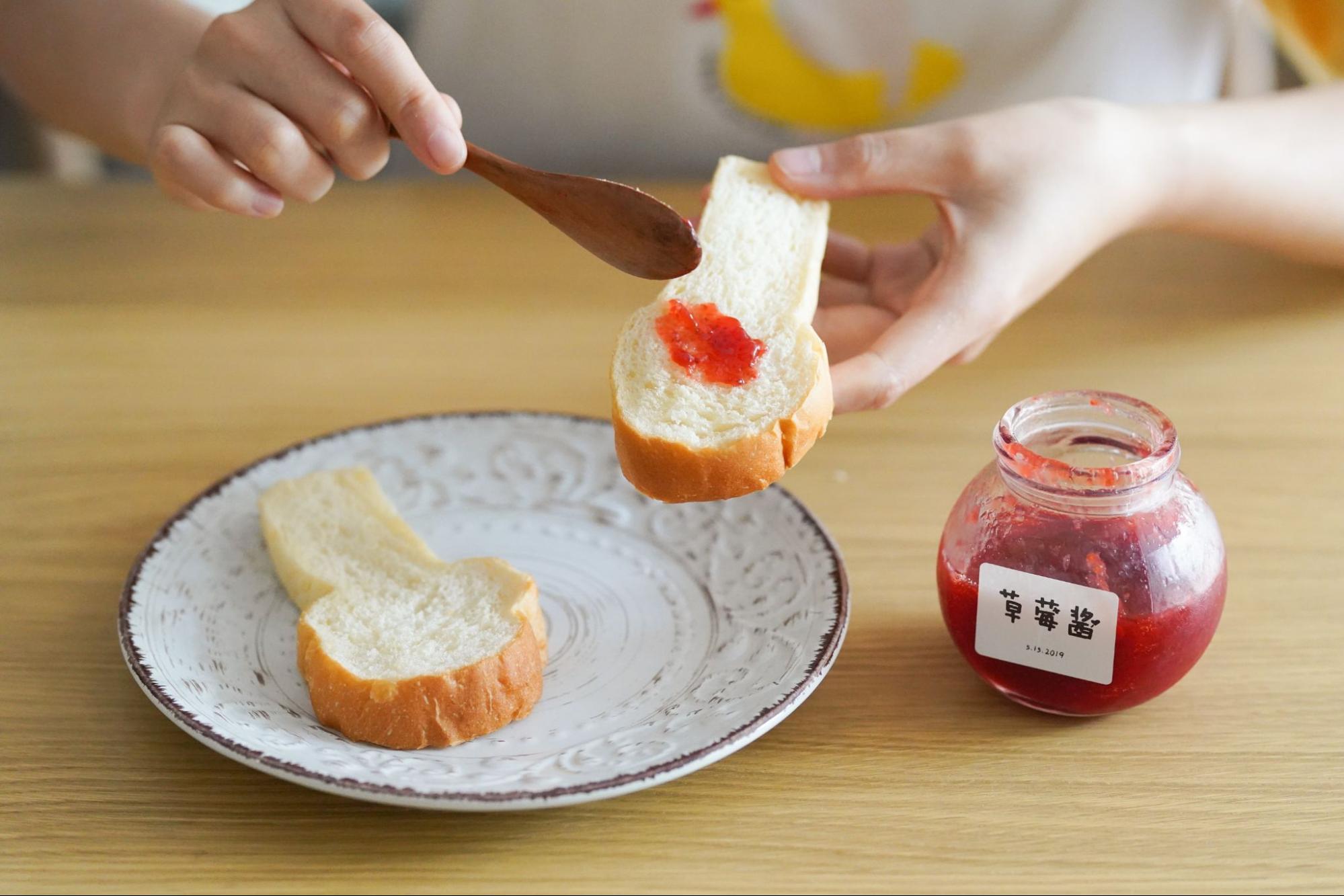 person-spreading-homemade-jam-on-bread