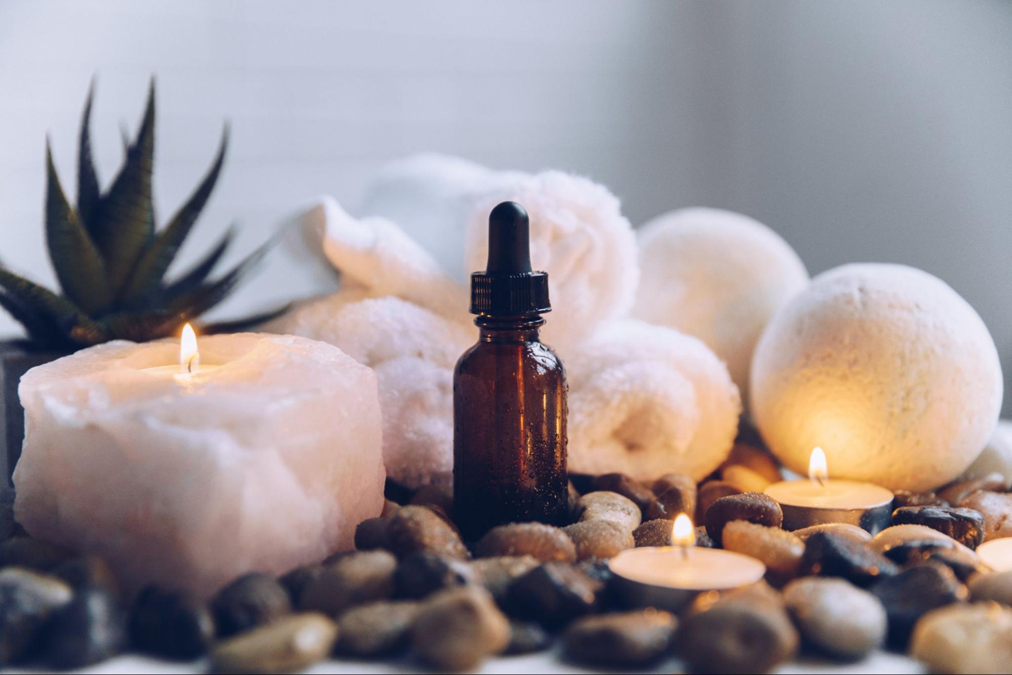 Photo of an essential oil bottle among candles and rocks