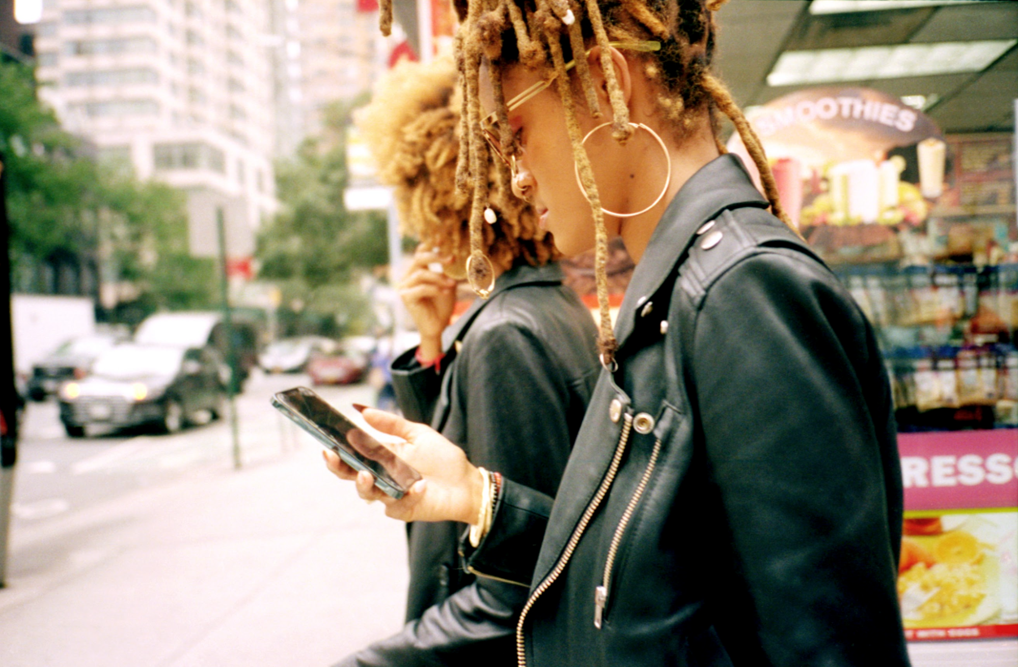 An image of Coco and Breezy on the street, attention focused on a phone