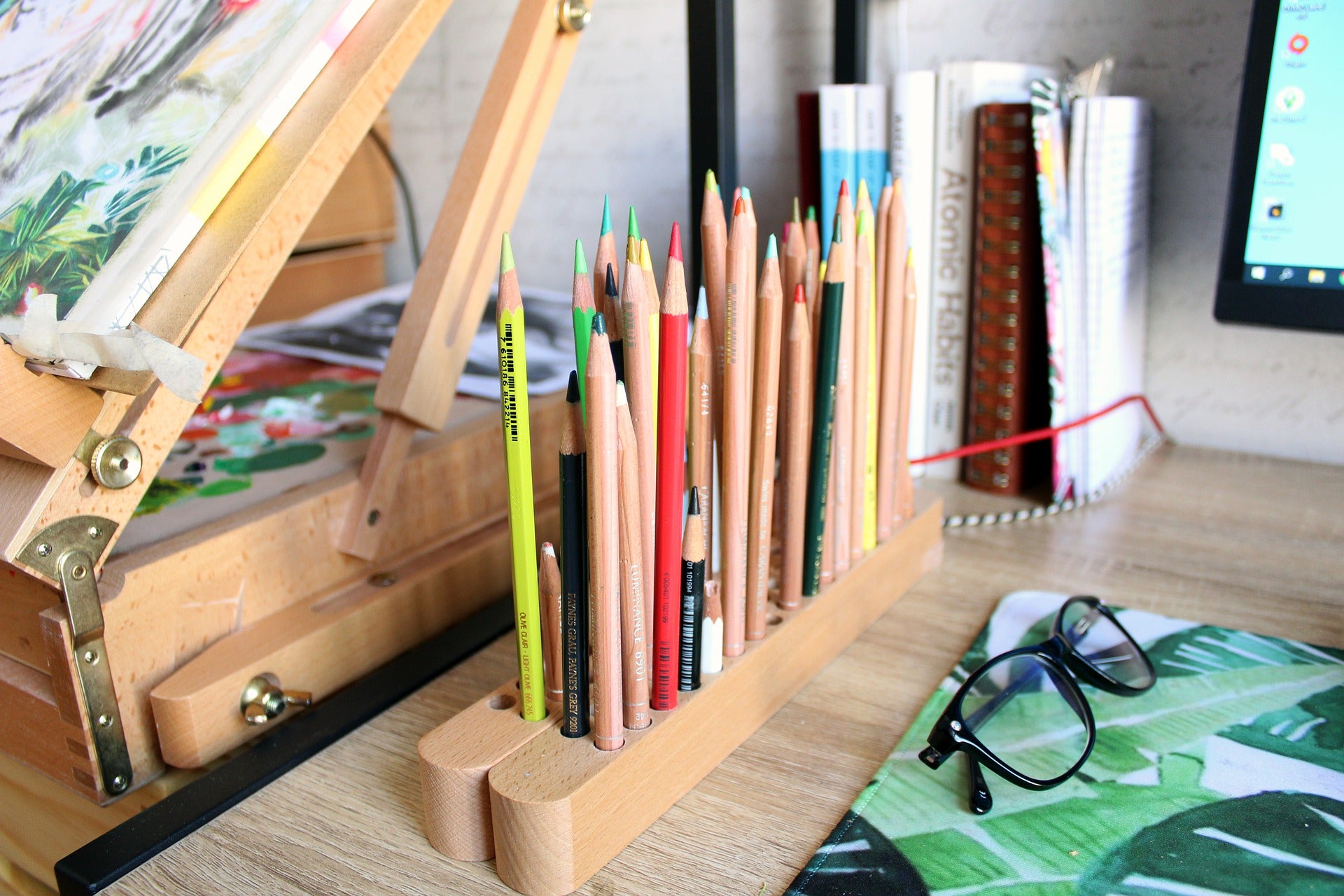 A pencil holder on a desk, containing pencils of different colors