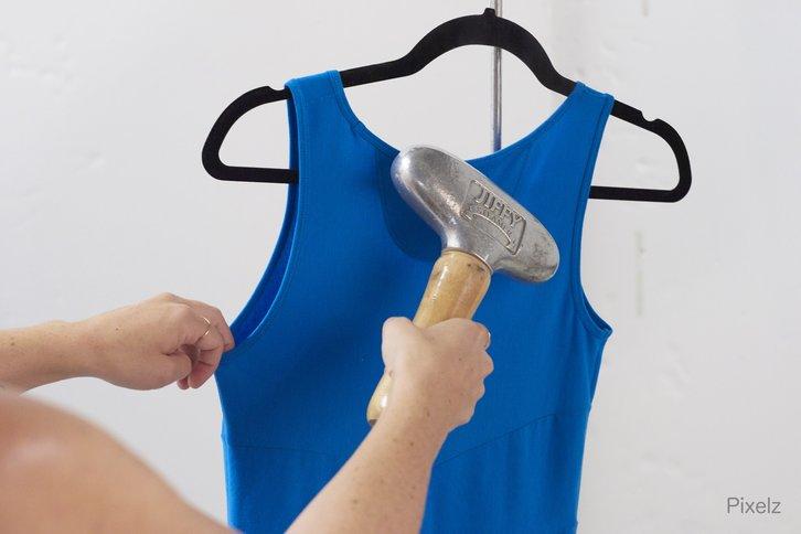 Eine Person bereitet ein blaues Kleid mit einer Fusselrolle für das Kleidungsfotoshooting vor.