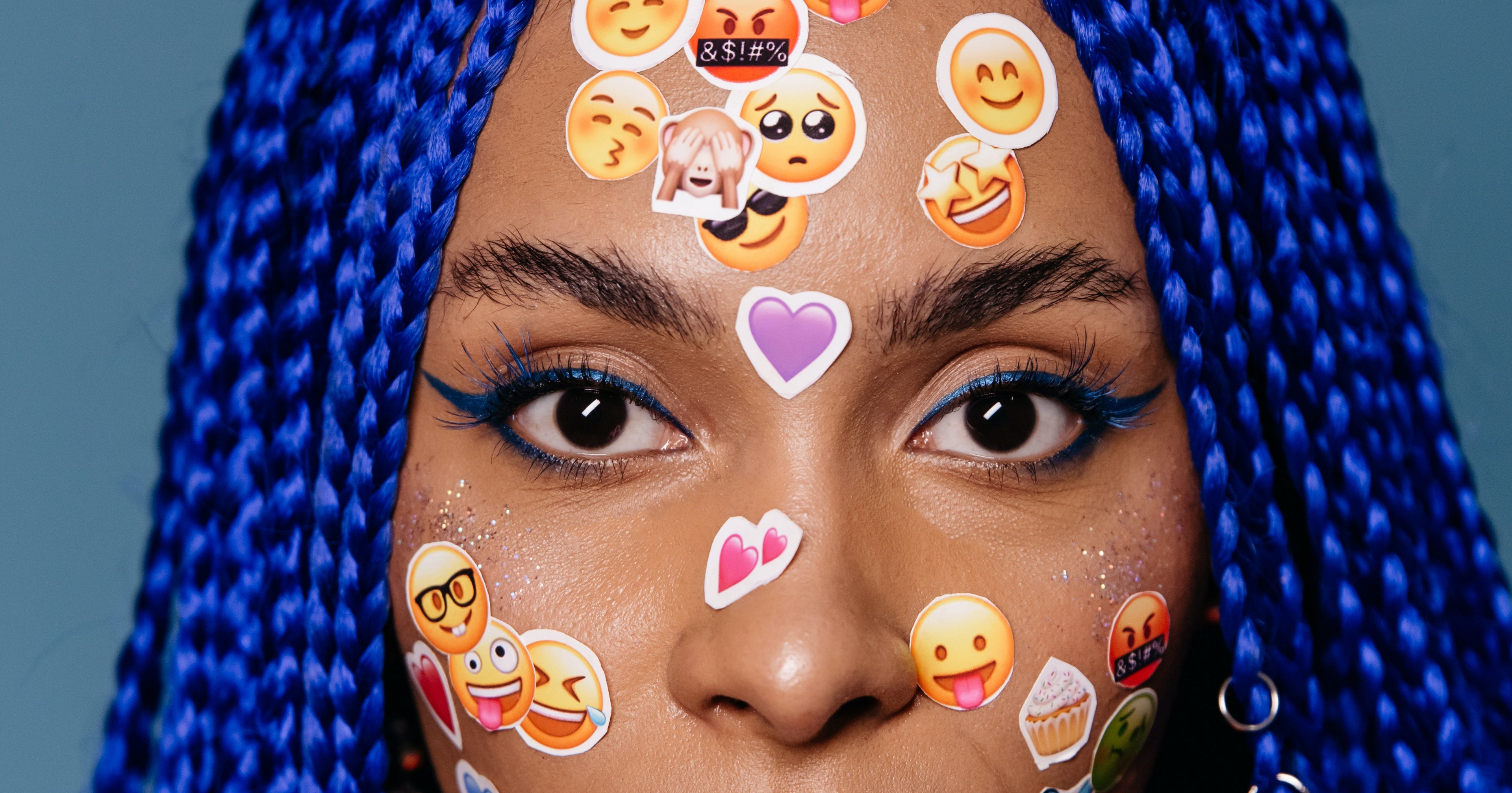 A woman's face positioned behind various Instagram stickers