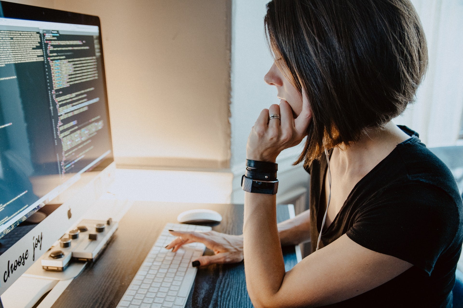 linkerprofiel van vrouw die aan een desktopcomputer zit en naar het scherm kijkt, code compileert: registreer een domeinnaam