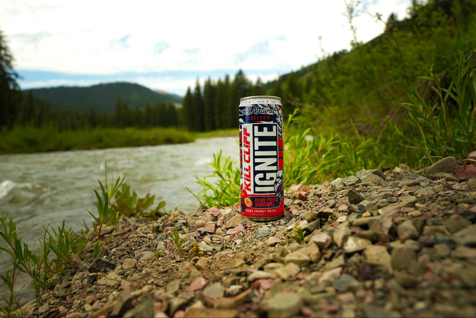 A bottle of Kill Cliff beverage backdropped by a river.