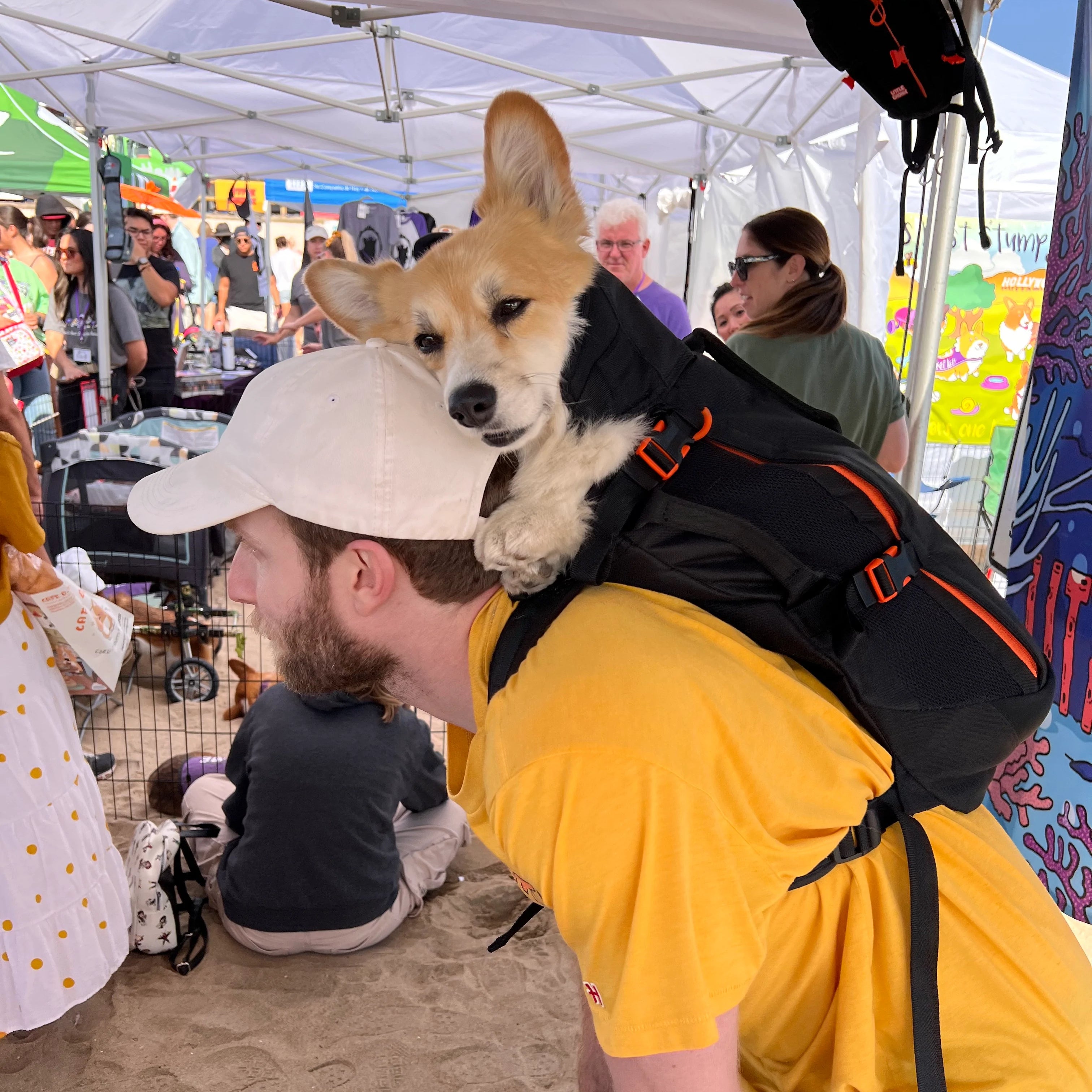 Bryan Reisberg, holding Maxine the corgi in a Little Chonk backpack, at Corgi Beach Day