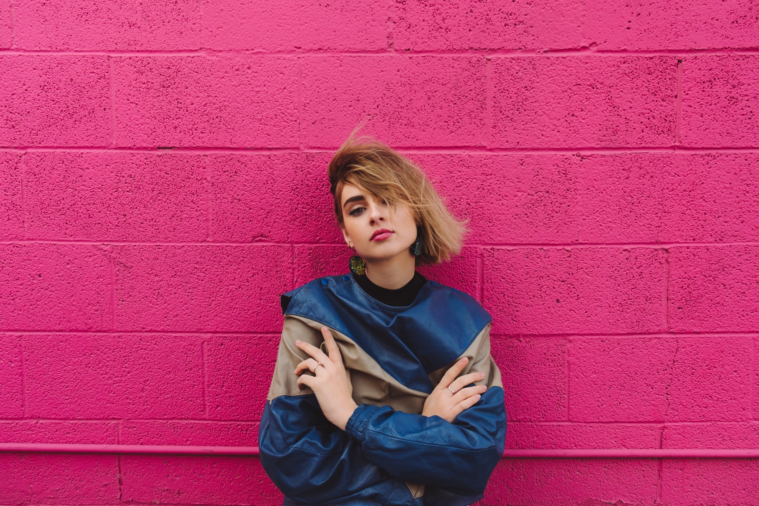 Person models a colorblock sweater against a pink wall