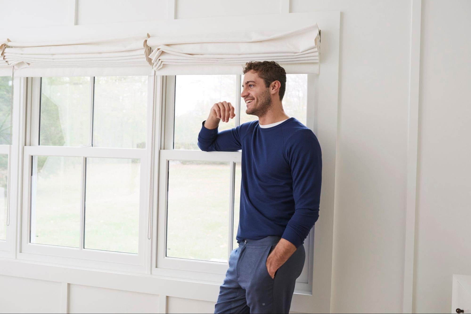 A model weaning a blue sweater and dress pants from Mack Weldon