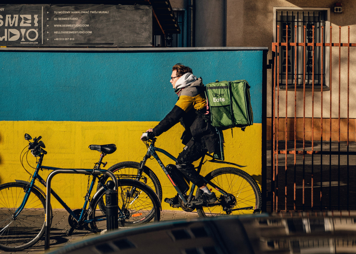 A courier bikes with a food delivery backpack 