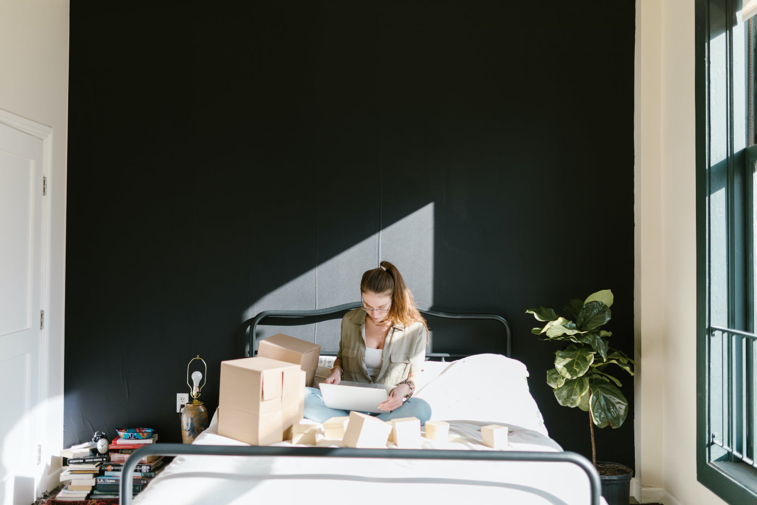 A person sits on a bed doing admin work