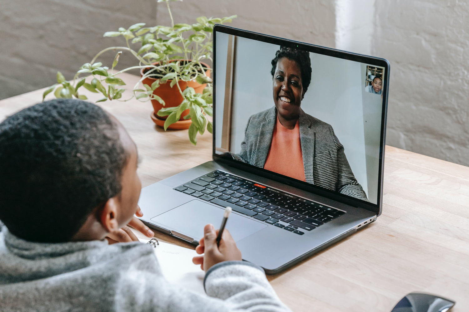 Een kind spreekt via een videochat op een laptop met een vrouw