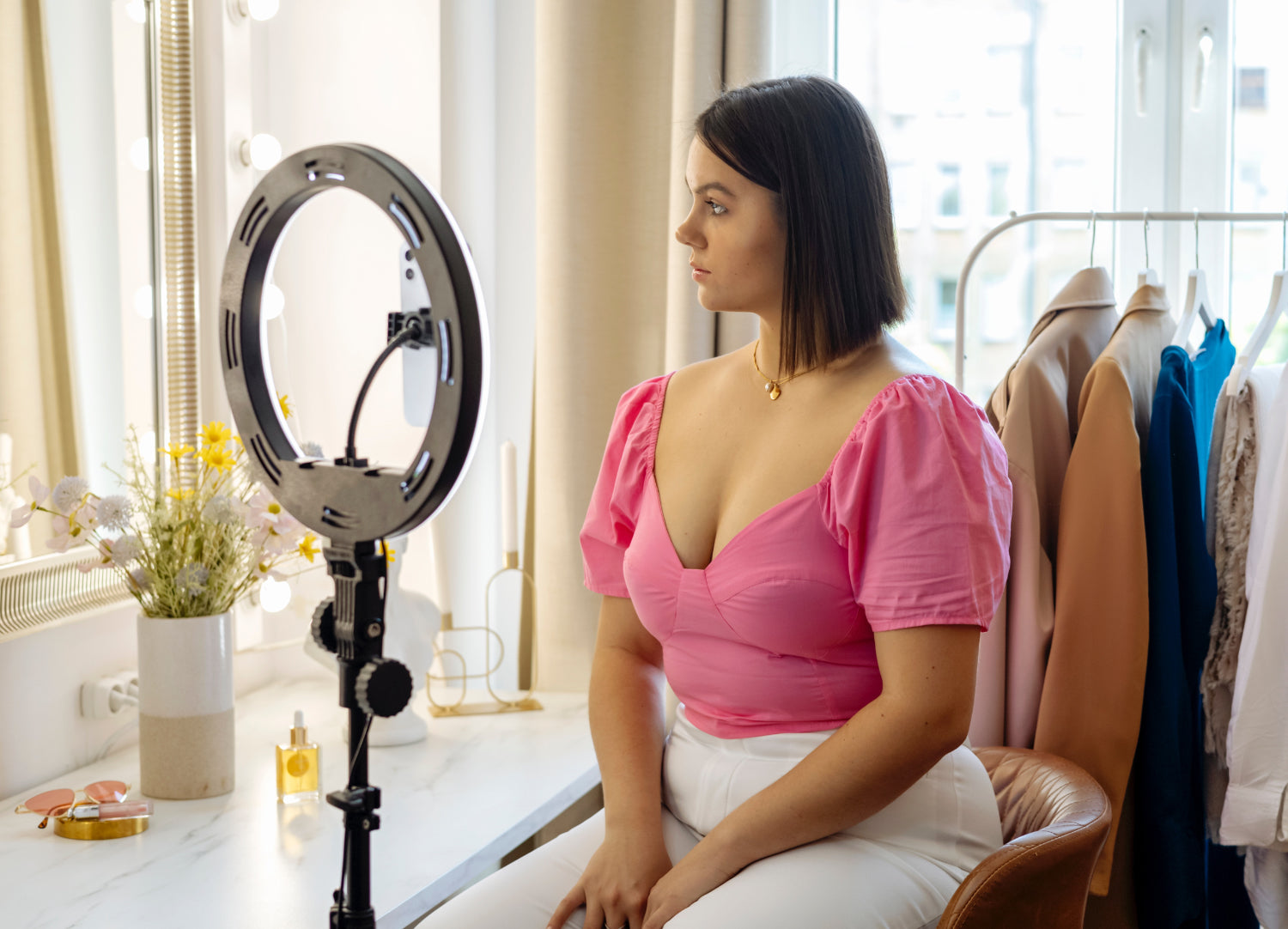 Woman sits in front of a tripod and ring light, shooting a YouTube video of herself