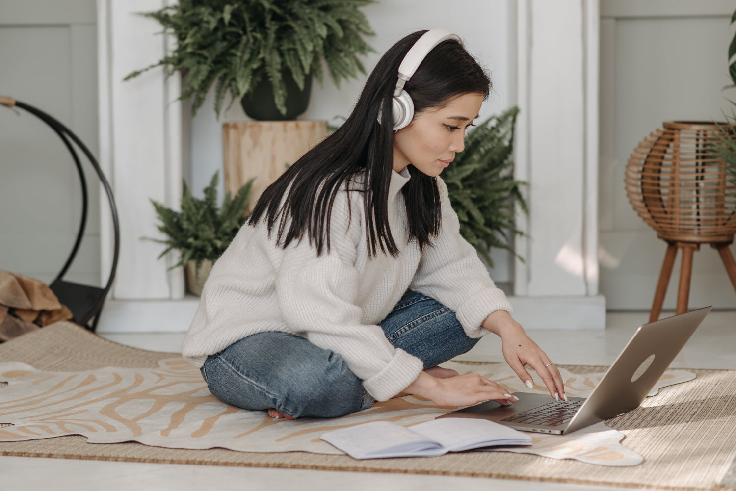 Person wearing headphones sits on the floor working at a computer