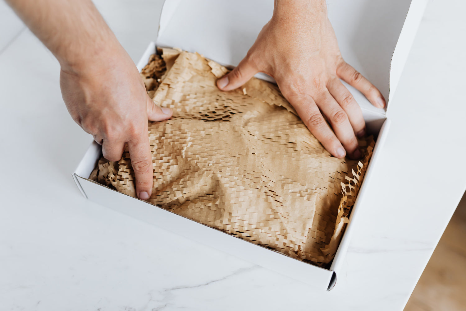 A person packs a box with packing material