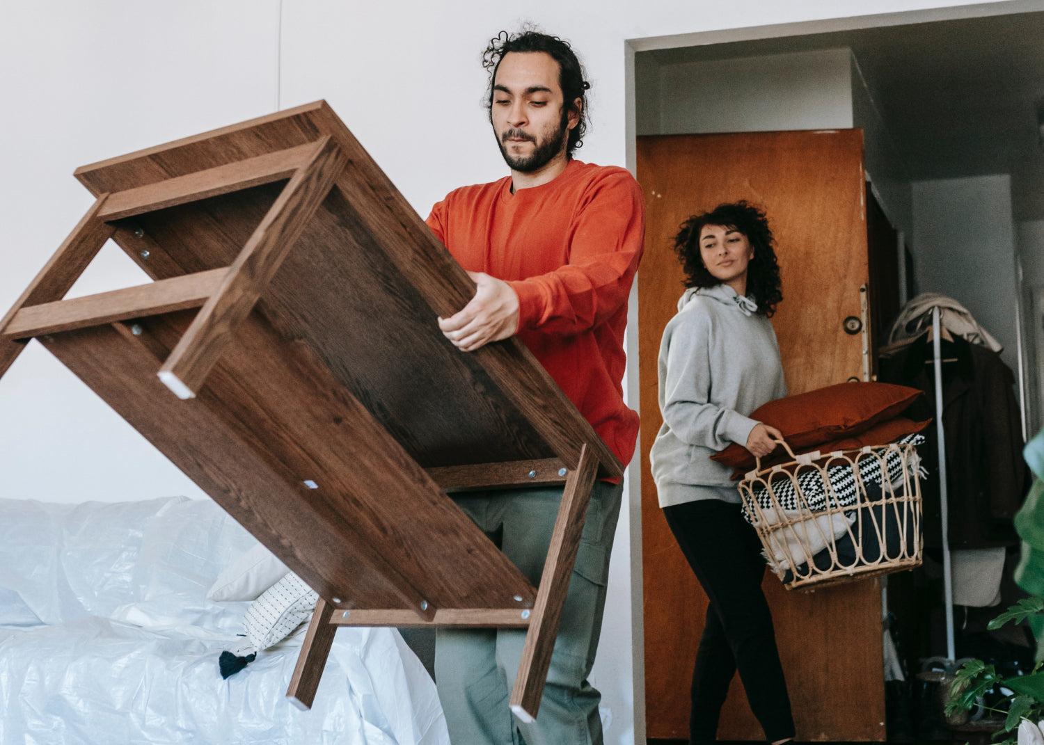 Two people move furniture in a home