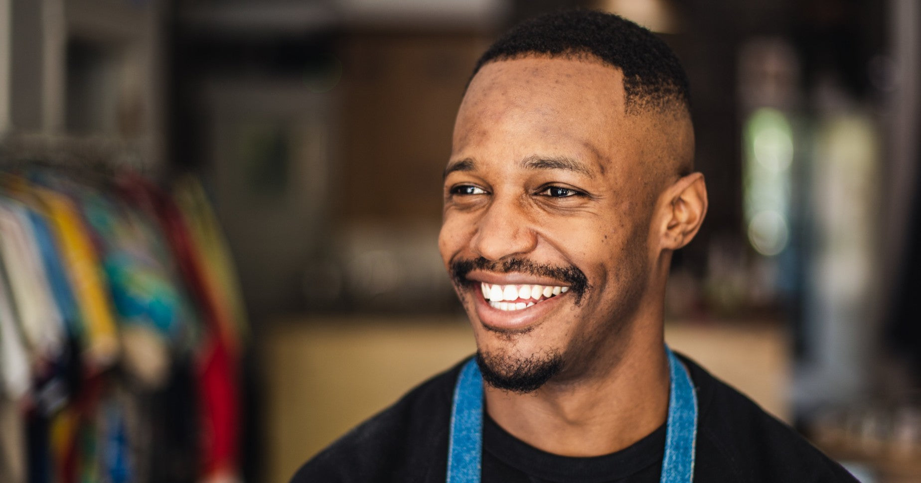 Smiling man standing in retail store near racks of clothing