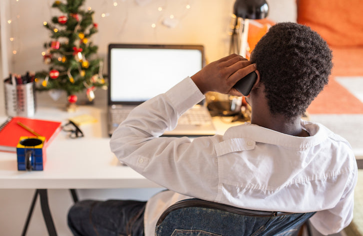 Eine Person telefoniert vor einem weihnachtlich dekorierten Laptop und kümmert sich um die Kundenbetreuung zu Weihnachten