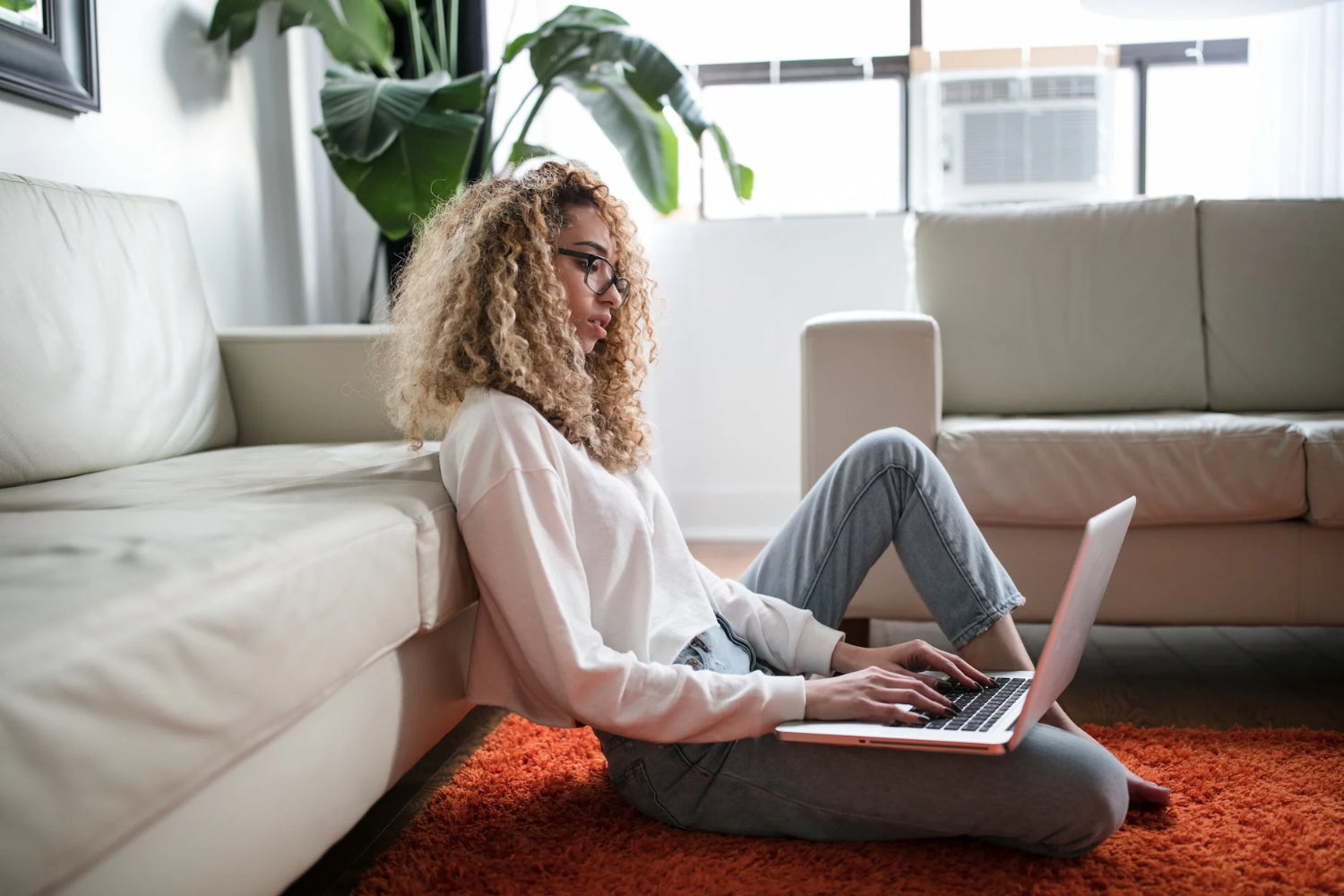 Woman writes on a laptop in a living room