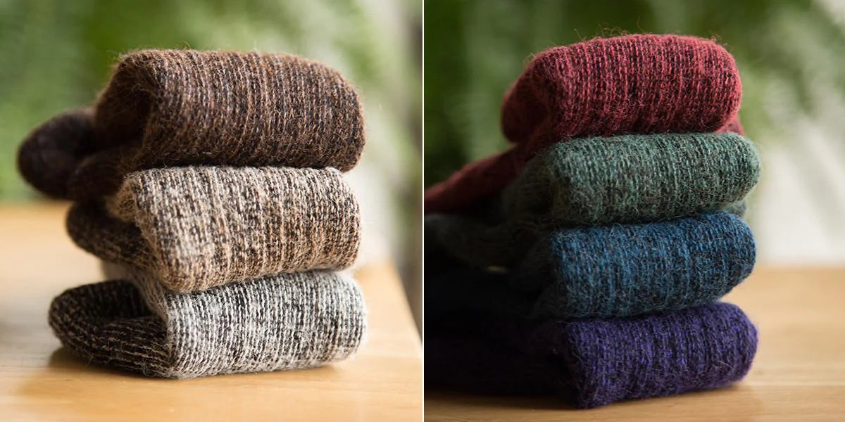 Alpaca wool knit socks in many colors stacked on a wood table