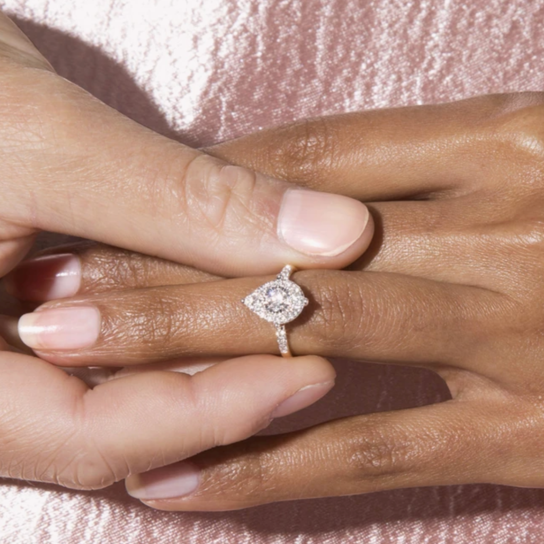 One person puts the Mia ring by Stone and Strand on another person's finger.