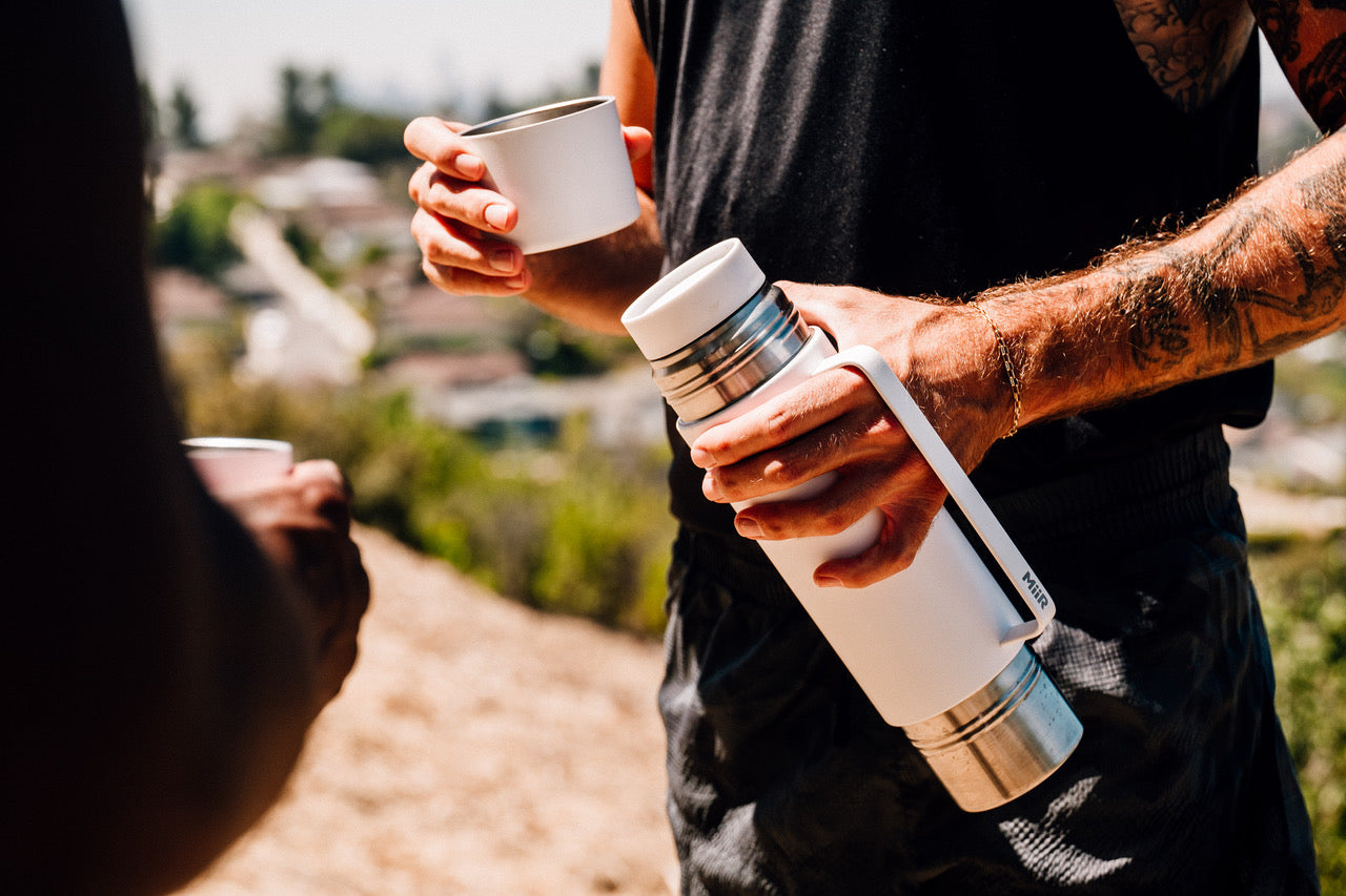 image of a MiiR thermos and mug set being held by a person in conversation with another person