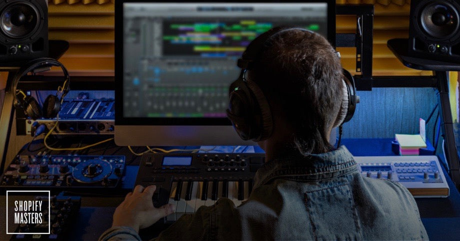 Production engineer edits music in front of a computer with headphones on.