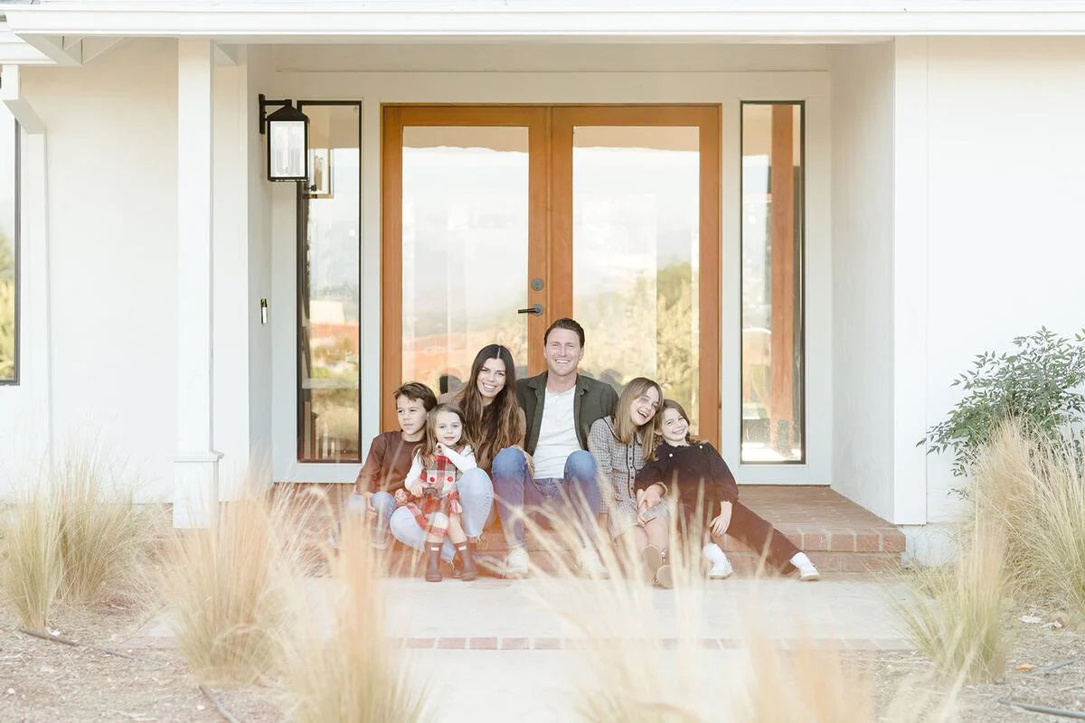 Elle Rowley sits on the stoop of a house with her kids and husband