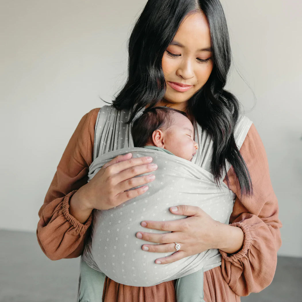 A woman cradles a baby in a baby-wearing wrap