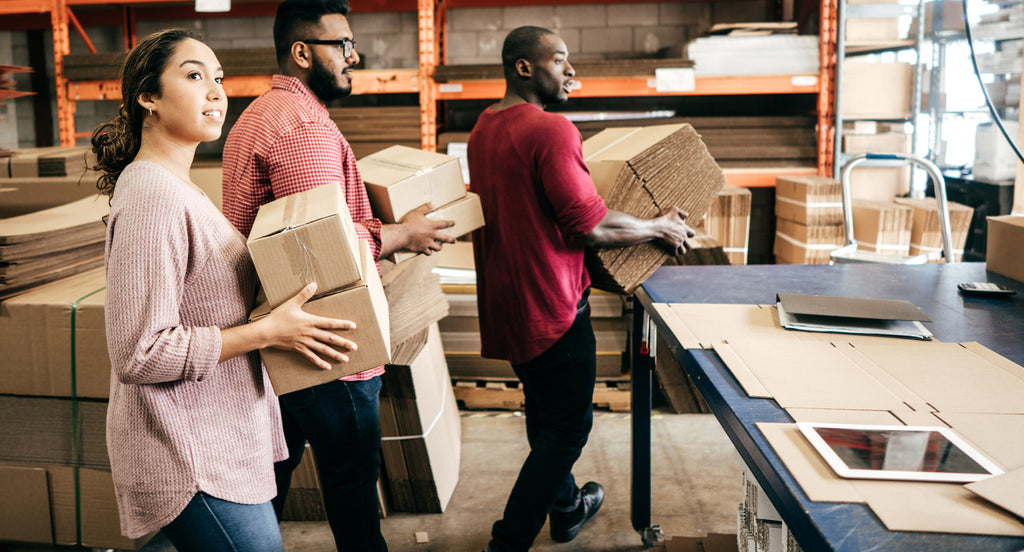 three people moving boxes in a warehouse