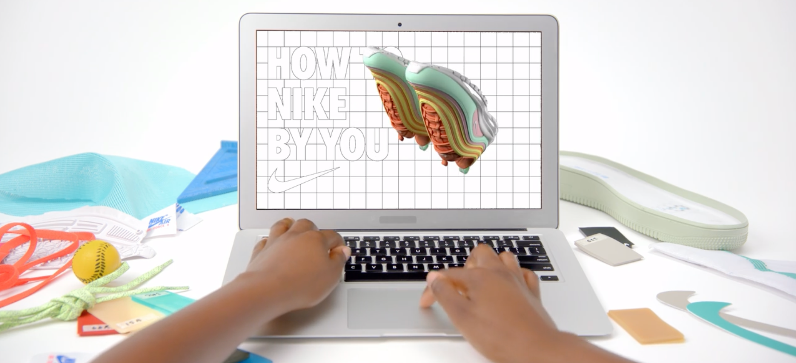 Nike's shoe customization tool being demoed on a laptop on a desk covered in fabrics and design tools