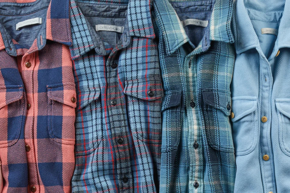 Four plaid mens shirts are arranged on a flat surface