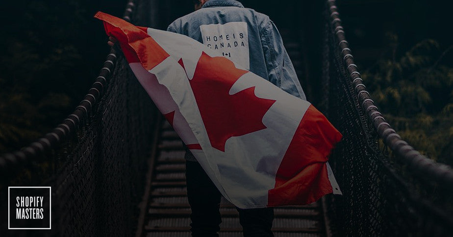 Model wears a "Home Is Canada" jeans jacket while posing with a Canadian flag. 