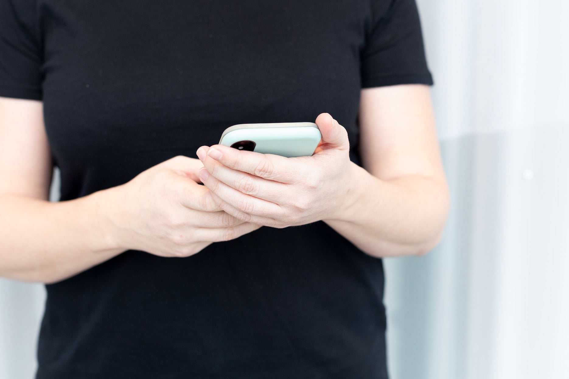 A person wearing a black shirt holds their phone